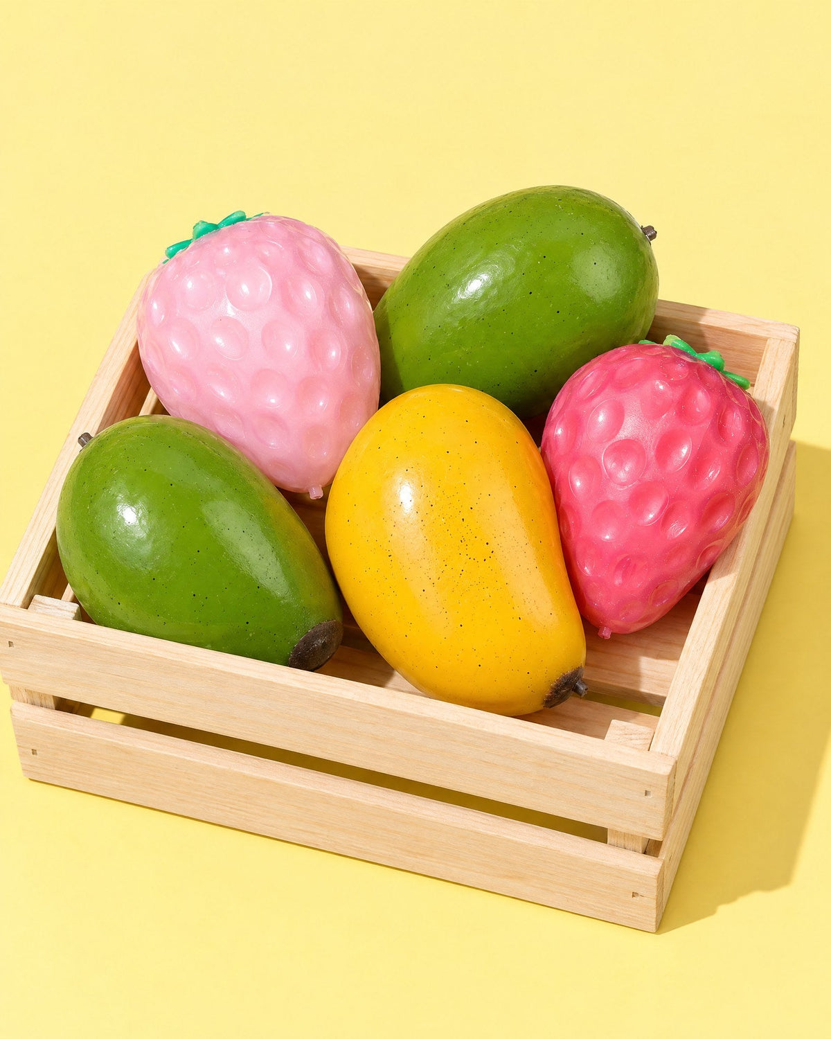 Mood Mango and Big Strawberry squishies in a small wooden crate