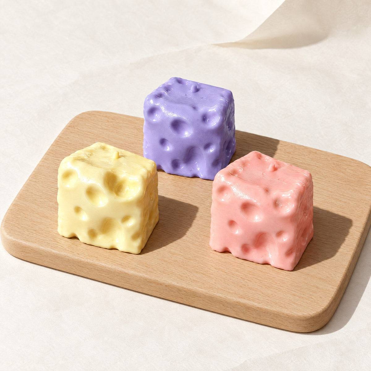 Yellow, pink and blueberry Dent Cheese squishies on a wooden board