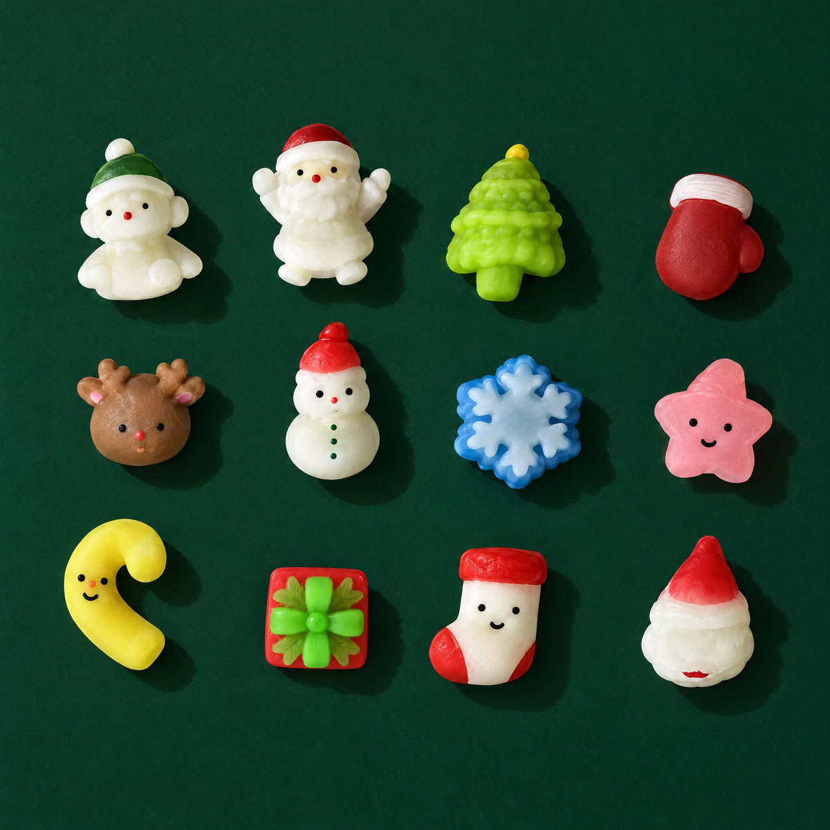 Twelve tiny Christmas mini squishies, including Santas, a snowman, a tree, a reindeer and a mitten, on dark green