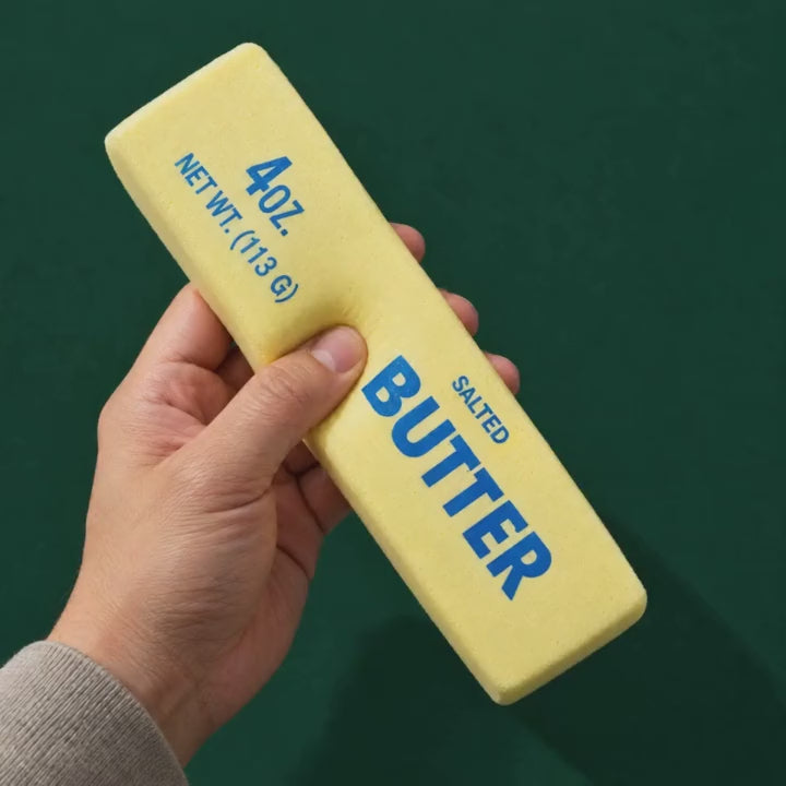 A thumb presses into the Butter Stick squishy and it slowly rises back