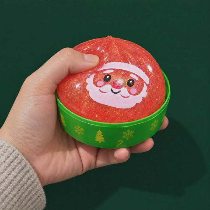 A hand squeezes the glittery Santa Holiday Bao squishy in its cup and it settles back