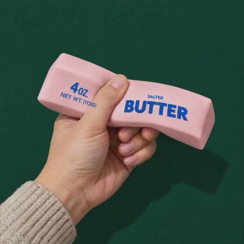 A hand squeezes the pink Crunch Butter squishy block and it springs back