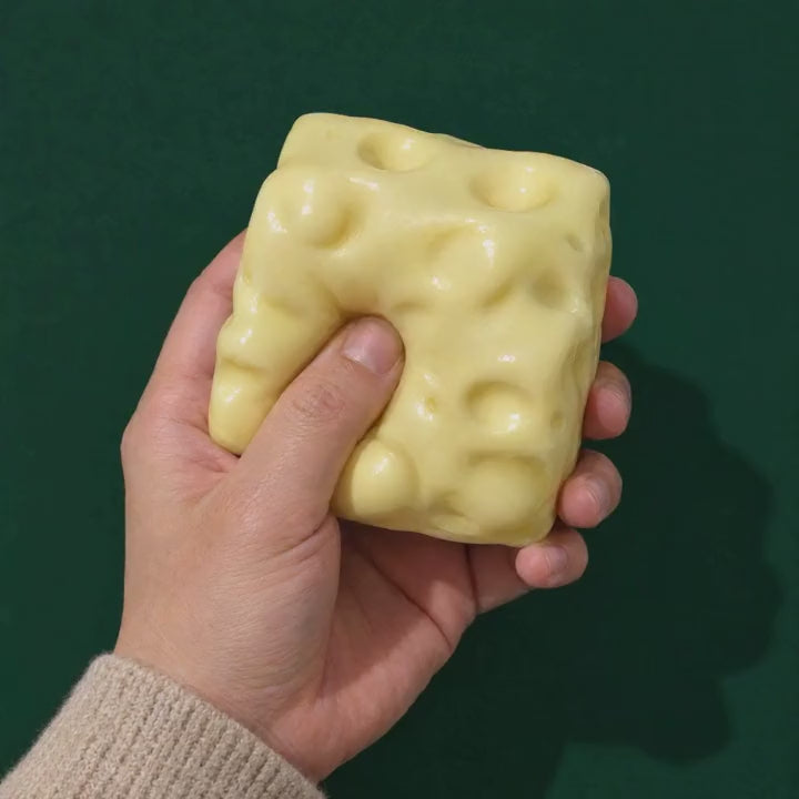 A hand squashes the Swiss Squish foam cheese and it slowly puffs back up