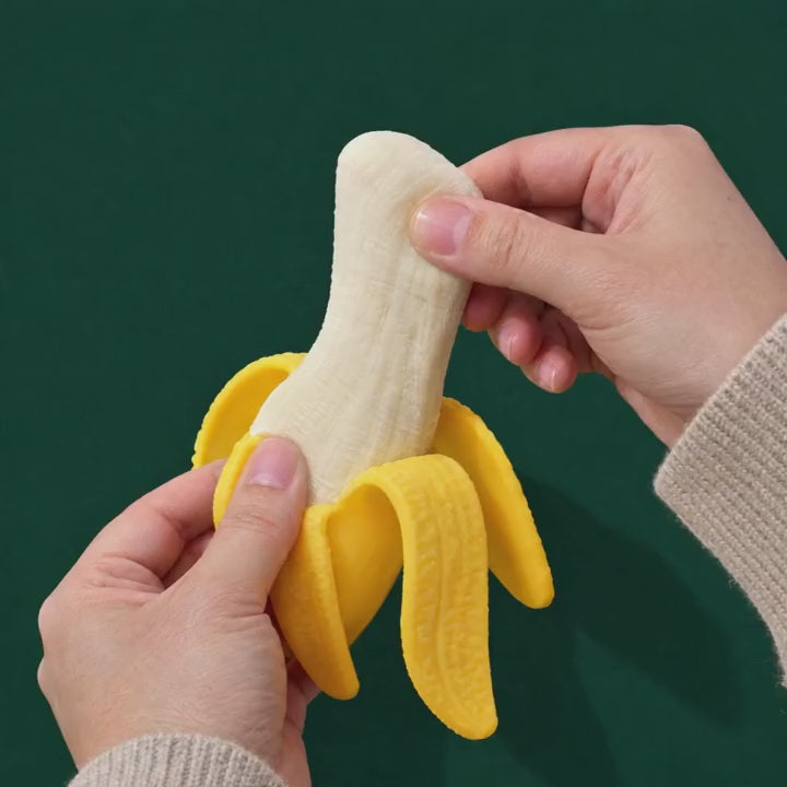 A hand gently stretches the soft banana inside the Peel-able Banana squishy