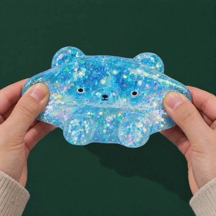 Two hands gently stretch the blue Glitter Bear and it jiggles back