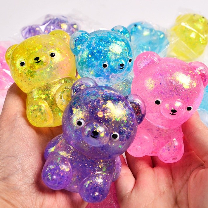 Real photo: pink, yellow, blue and purple glitter-gel bear squishies held together in two adult hands