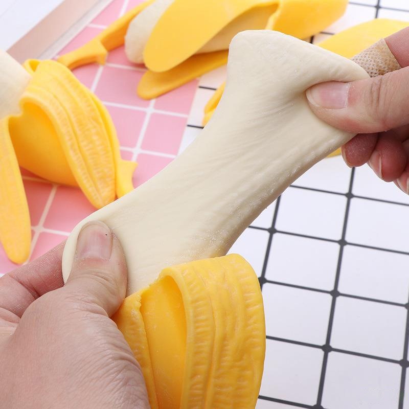 Real supplier photo: two hands stretching the pale banana of the squishy out of its yellow peel