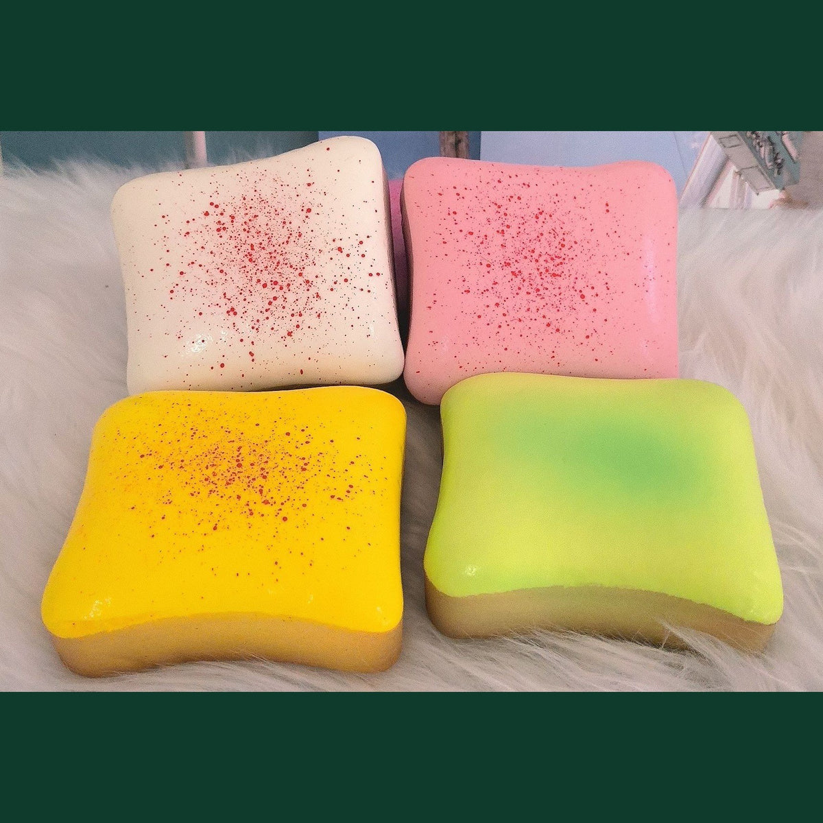 Real photo of the cream, strawberry, cheese and matcha toast squishies side by side on white fur