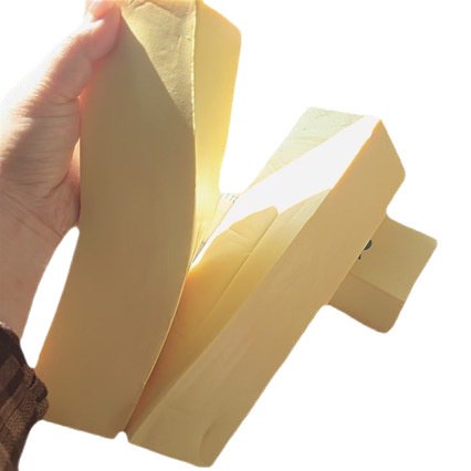 Real photo: a hand bending the soft foam butter stick almost in half
